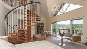 A spacious living area with a curved staircase, a large window offering a view of the outdoors, and a dining area with a table and chairs. - Duplex Penthouse Aparthotel Rosa (Podcetrtek)