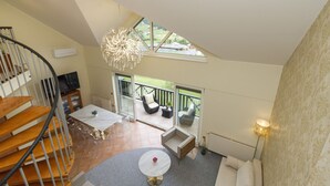 A spacious living area with a staircase, a dining table, and a sofa. There is a balcony with outdoor seating and a view of the outdoors. - Duplex Penthouse Aparthotel Rosa (Podcetrtek)