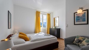 Una camera da letto con un letto, un comodino con una lampada, una cassettiera e un divano.