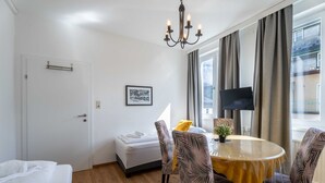 Una camera d'albergo con un letto, un tavolo da pranzo con sedie, una televisione e una finestra con tende.