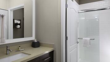 A bathroom with a sink, mirror, towel rack, and a glass shower enclosure.