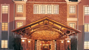 A large brick building with a central entrance, multiple windows, and a distinctive roof structure. - Staybridge Suites Cedar Park - Austin N by IHG (Cedar Park)