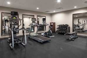 Un gimnasio con cintas de correr, elípticas y bancos de pesas.