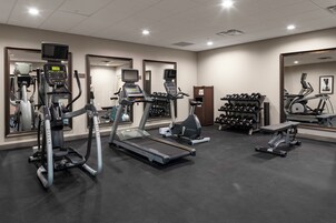 A gym with treadmills, elliptical machines, and weight benches.