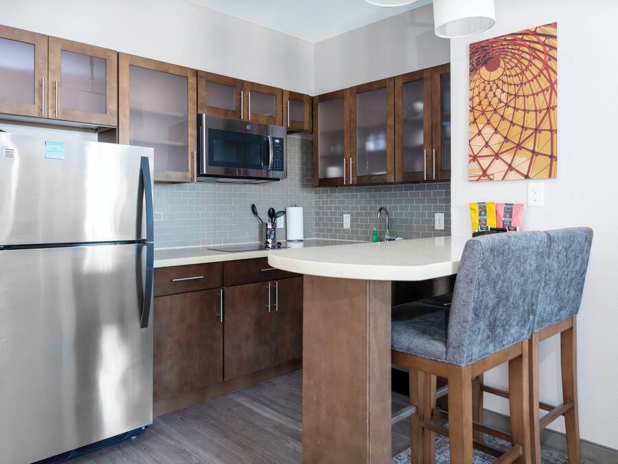 Cozinha compacta com geladeira, micro-ondas e armários de madeira.