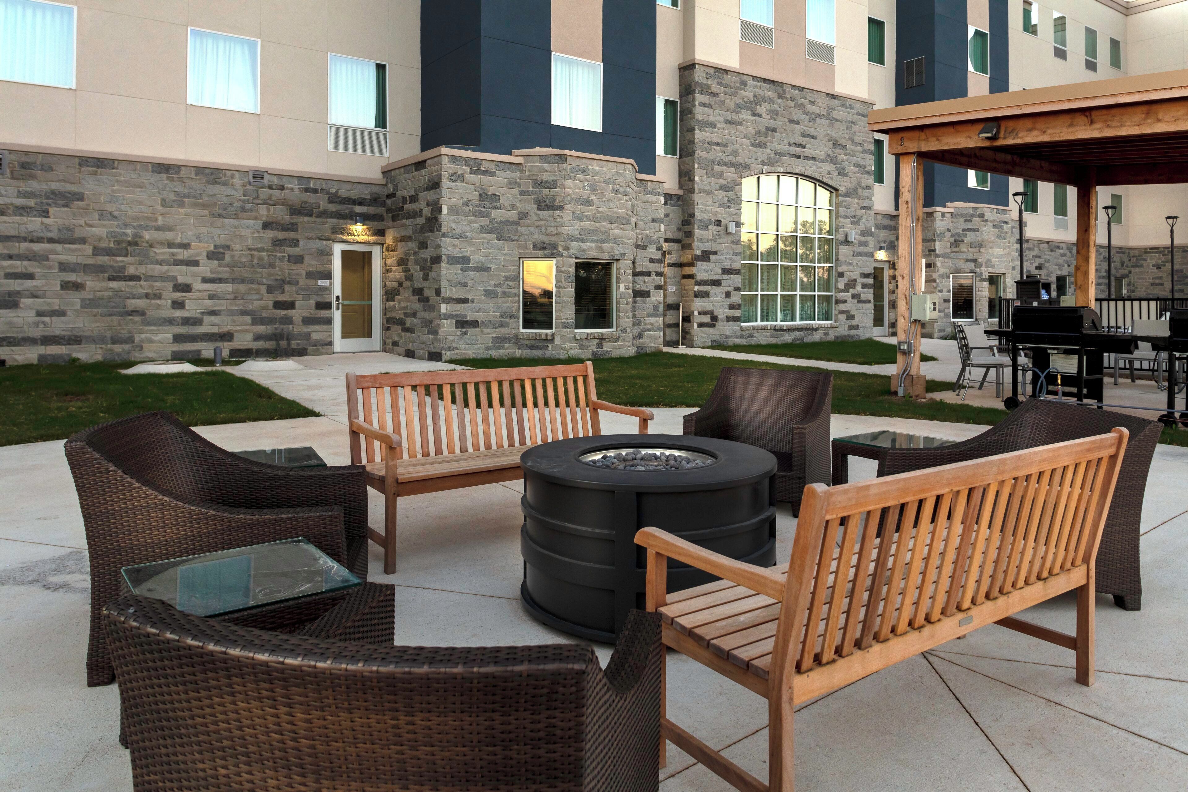 An outdoor seating area with wicker furniture and a fire pit.