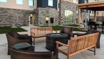 An outdoor seating area with wicker furniture and a fire pit.