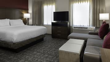 A hotel room with a large bed, a flat-screen TV, a desk, and a sofa.