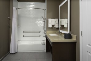 Une salle de bain moderne avec une baignoire blanche, un lavabo beige et un grand miroir.