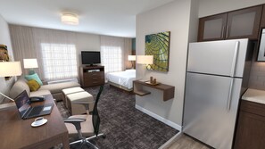 Une chambre d’hôtel équipée d’un lit, d’un bureau avec un ordinateur portable, d’un réfrigérateur et d’une télévision.