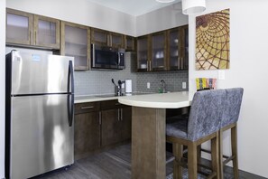 Une cuisine moderne dotée d’appareils électroménagers en acier inoxydable, de meubles en bois et d’un tabouret de bar.