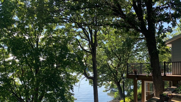 Ein Seeufergrundstück mit Holzterrasse, Steinstufen und Blick auf das Wasser.