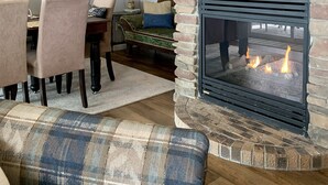 Ein gemütliches Wohnzimmer mit Kamin aus Stein, einem Essbereich mit Stühlen und einer Couch.