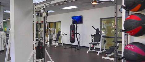 A gym with various exercise equipment, including a squat rack, bench press, and punching bags.