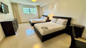 A hotel room with two beds, a TV, a dresser, and a window with curtains. - Sunny Isles apartment hotel (Sunny Isles Beach)