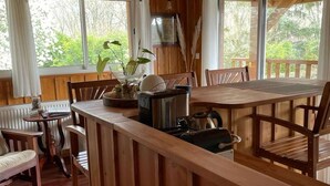 Interno di una baita in legno con zona pranzo, cucina e ampie finestre.