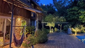 Una casa in legno con patio, immersa tra alberi e piante.