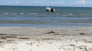 A beach with a boat on the water and a sandy shore. - Strandby Badehotel (Strandby)