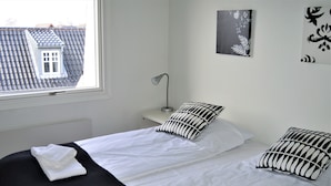 A hotel room with a bed, a nightstand, a lamp, and artwork on the wall. - Strandby Badehotel (Strandby)