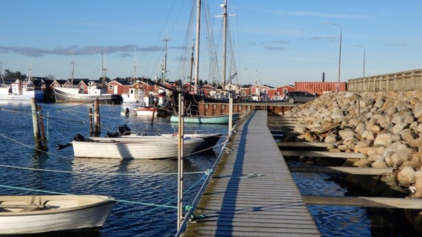 A marina with boats docked, a wooden walkway, and a stone wall. - Strandby Badehotel (Strandby)