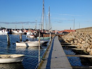 A marina with boats docked, a wooden walkway, and a stone wall. - Strandby Badehotel (Strandby)