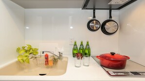 A kitchen with a sink, a plant, a red pot, and three green bottles. - Vacation Rent Kanayama (Nagoya)