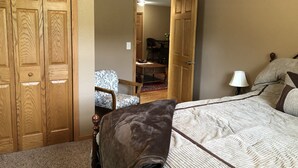 Ein Schlafzimmer mit Bett, Stuhl, Kleiderschrank und einer offenen Tür zu einem Essbereich.