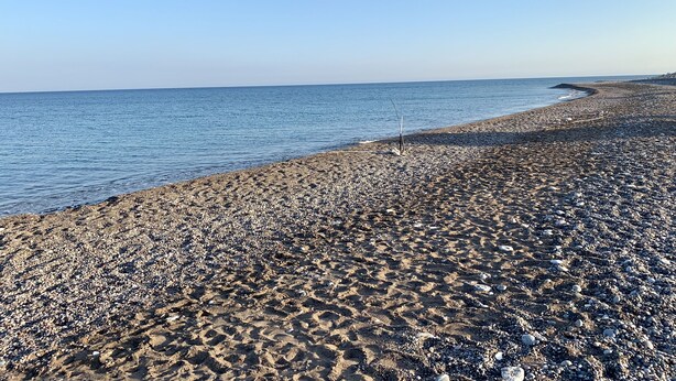 En strand med småsten och fri sikt ut över havet.