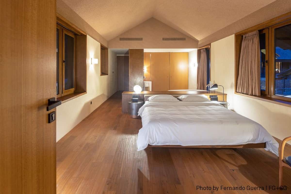 Une chambre d’hôtel moderne avec un grand lit, un plancher en bois et une vue sur l’extérieur.