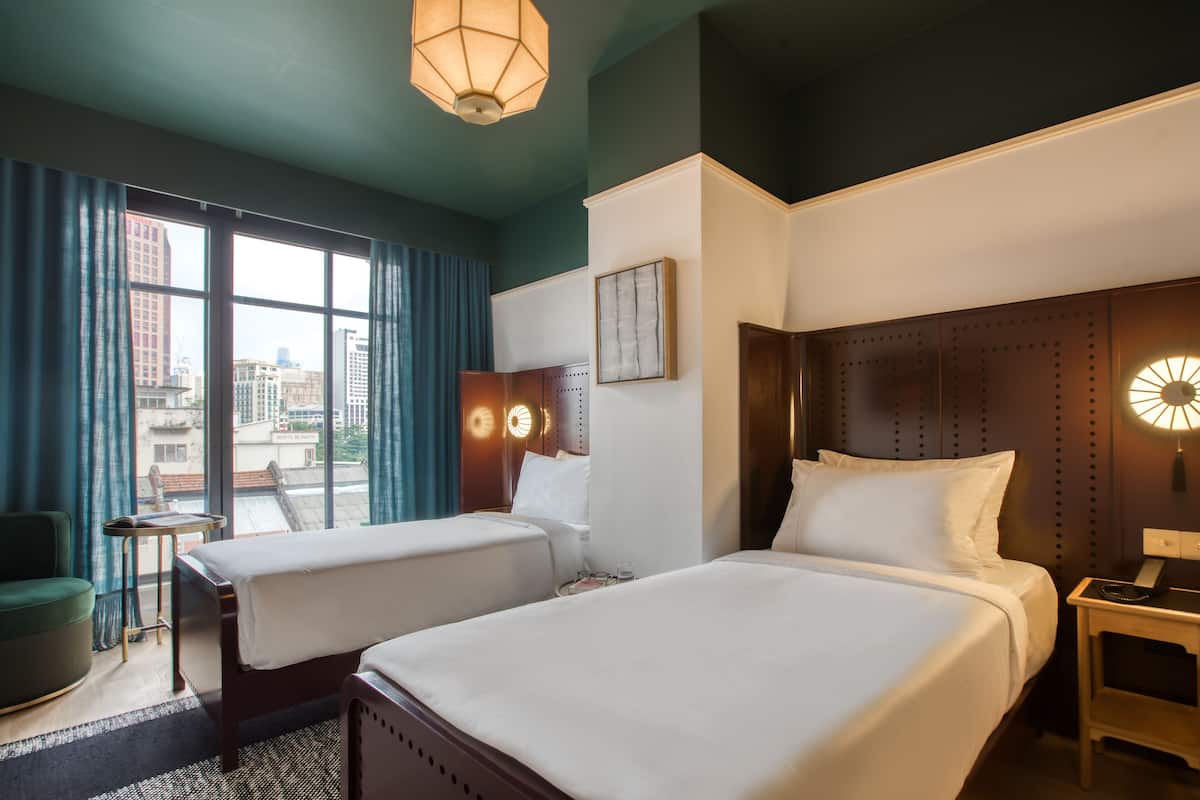 Une chambre d’hôtel avec deux lits, une vue sur la ville et un design moderne.