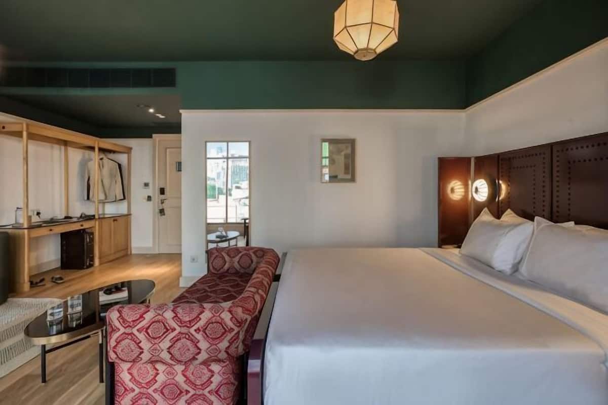 Une chambre d’hôtel avec un grand lit, un canapé, une petite table et un coin cuisine.