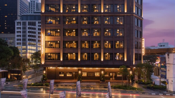 Een hotel met meerdere verdiepingen, modern vormgegeven, met veel ramen en een goed verlichte gevel.