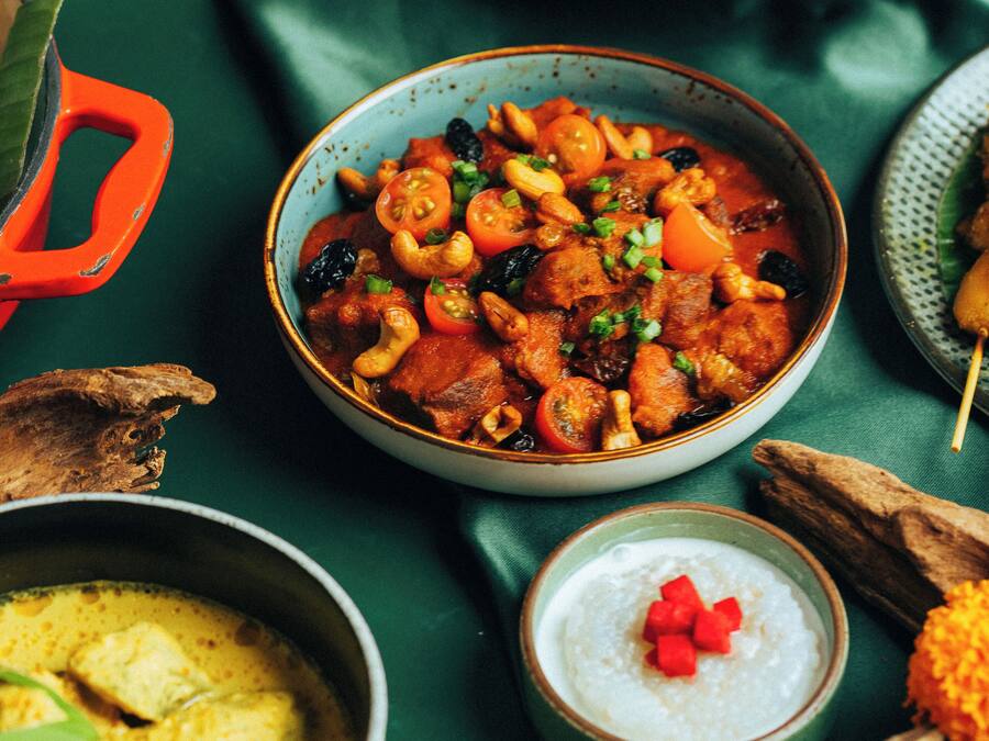 A variety of dishes including a bowl of curry, a plate of meat, and a bowl of rice.