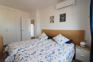 A bedroom with a bed, a nightstand, a wardrobe, and an air conditioning unit.