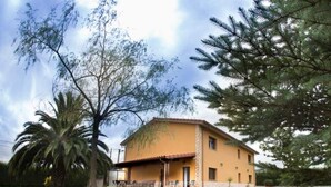 A two-story house with a patio, surrounded by trees and a lawn.