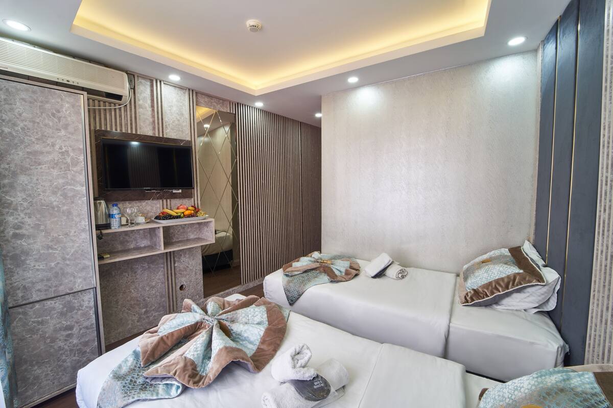 A hotel room with two beds, a TV, a minibar, and a mirror.