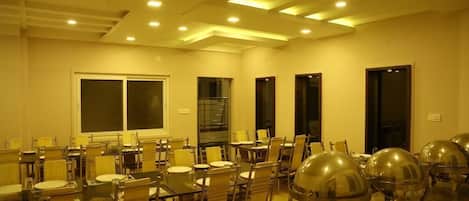 Un salón de conferencias con mesas y sillas, un ventanal grande y una puerta.