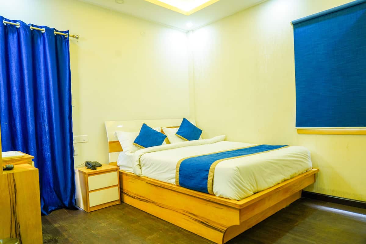 Een slaapkamer met een houten bed, een nachtkastje, een telefoon en een blauw gordijn.