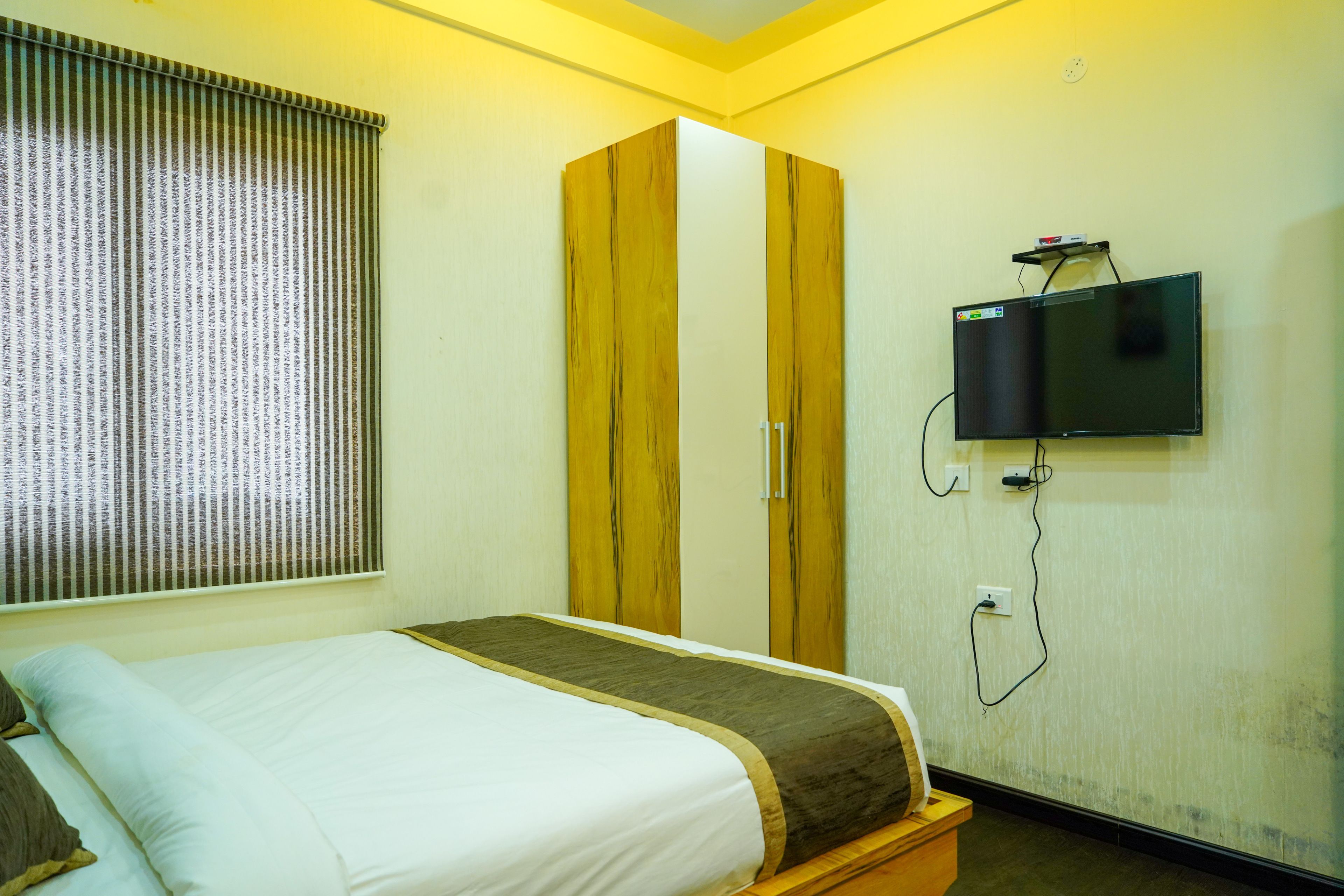 Ein Hotelzimmer mit einem Bett, einem Kleiderschrank und einem an der Wand befestigten Fernseher.