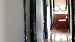 Un pasillo con piso de madera, paredes blancas y puertas enmarcadas en negro.
