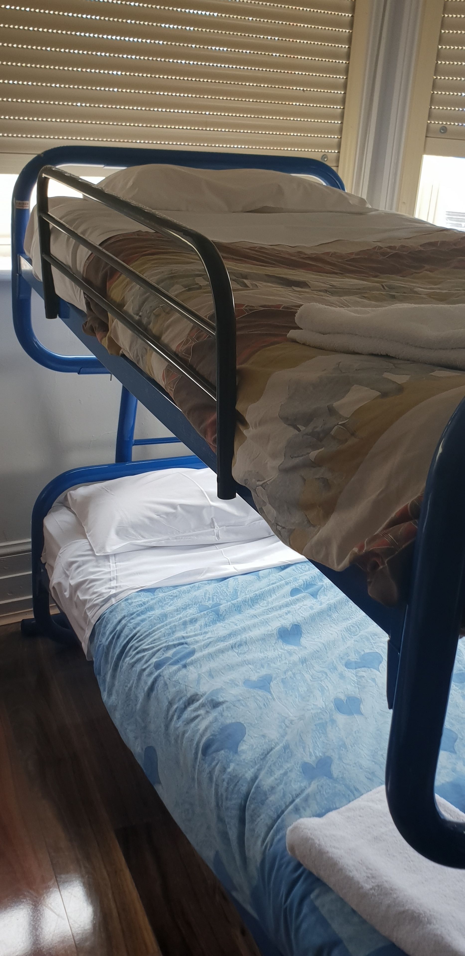 A bunk bed with a patterned mattress, a blue headboard, and a blue bedspread with a heart pattern.