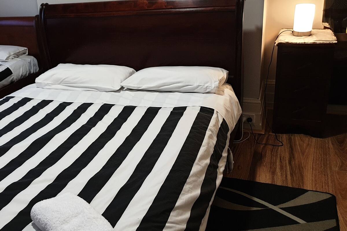 Two single beds with black and white striped bedding, a wooden headboard, and a bedside lamp.
