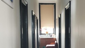 Un pasillo con suelo de madera, puertas de marco negro y un ventilador de techo.