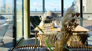 A modern outdoor seating area with wicker chairs, a wooden table, and a vase with dried plants. - Stunning home in Lembruch/Dümmer See with sauna (Lembruch/Dümmer See)