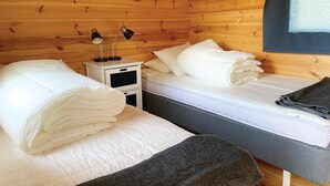 A small, cozy room with two beds, a nightstand, and a lamp.