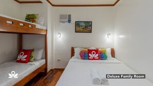 A Deluxe Family Room with a bunk bed, a single bed, a painting on the wall, and a ceiling light fixture. - Balay Paragua Annex (El Nido)