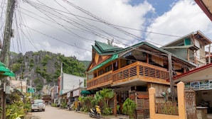 A two-story building with a balcony, a parked scooter, and a car on the street. - Balay Paragua Annex (El Nido)