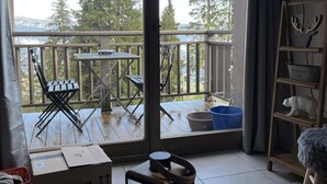 A balcony with a view of trees and mountains, a wooden deck, and a table with chairs. - E203 - 45 m2 - 2P+cab - 4/6 pers (Prapoutel)