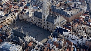 Una plaza histórica en el centro de la ciudad, rodeada de arquitectura europea tradicional, incluyendo una catedral destacada y un edificio alto y ornamentado.