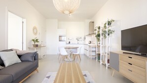 Una sala de estar moderna con un sofá, televisor y un comedor con sillas y una mesa.